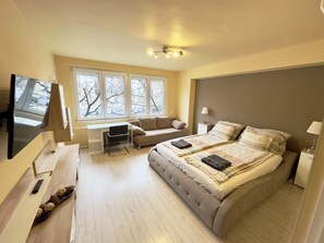 A modern bedroom with a large bed, a desk, a sofa, and a TV. - Brand new apartment in the center (Budapest)