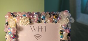 Um adorno com a palavra "WIFI" e o símbolo de Wi-Fi, rodeado por contas coloridas e detalhes decorativos.