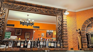 A bar area with a mirror, a chandelier, and a brick wall. - Casa Oasa  (Koper)