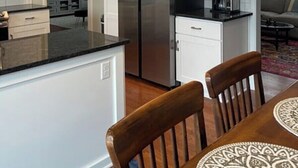 Una cocina moderna con armarios blancos, un refrigerador de acero inoxidable y una cafetera sobre la encimera.