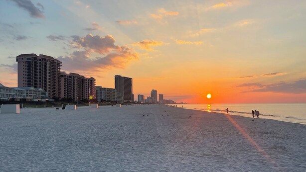 A beach with buildings in the background. - Cozy 2-bedroom townhome with AC, WiFi walk to Orange Beach (Orange Beach)