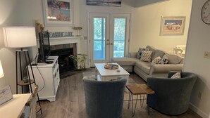A modern living room with a fireplace, a sofa, a coffee table, and a lamp. - Cozy 2-bedroom townhome with AC, WiFi walk to Orange Beach (Orange Beach)