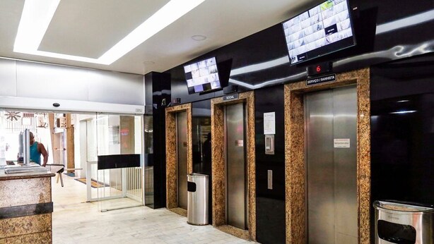 Un área de ascensores moderna con ascensores con encimera de granito, una pantalla digital en la parte superior y un cubo de basura.