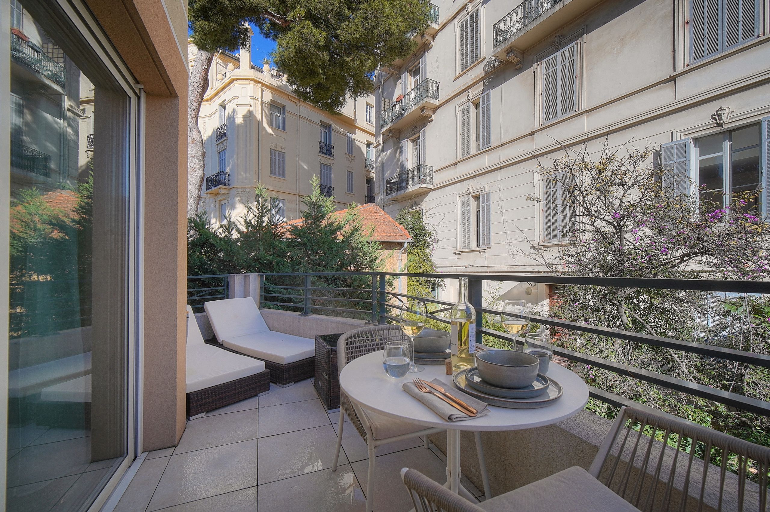 A balcony with a table set for dining, outdoor seating, and a view of the cityscape.