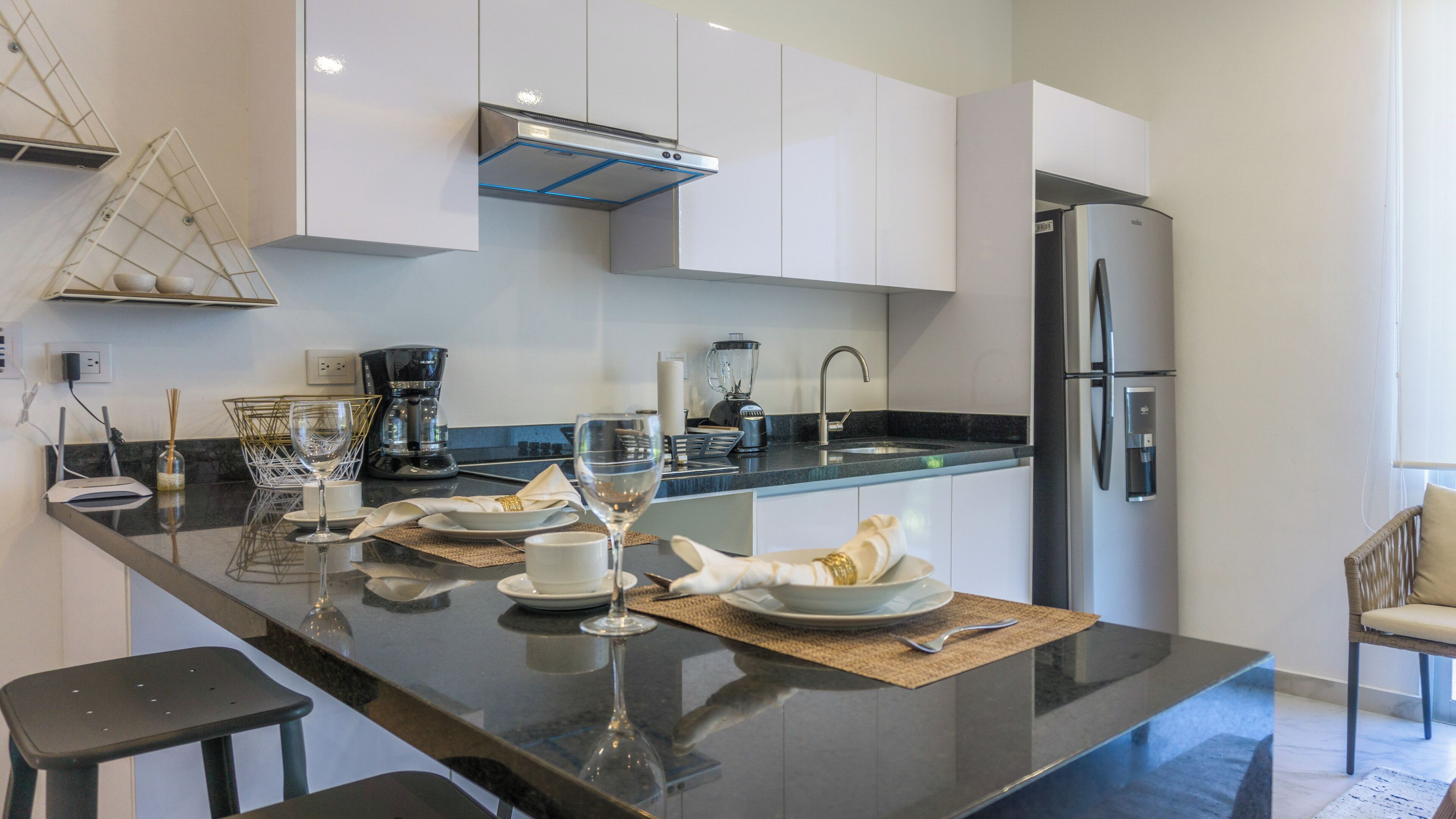 A modern kitchen with a central island, stainless steel appliances, and white cabinetry.