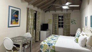 A bedroom with a bed, a desk, a chair, a ceiling fan, and a television. - Villa Mia Apartment Studio #4 (Oistins)