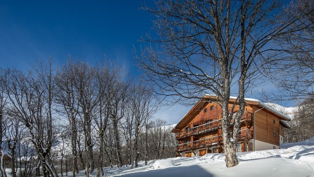 A wooden chalet with a balcony, surrounded by snow-covered trees and a clear blue sky. - Apartment in Saint-Sorlin near Ski Resort (Saint-Sorlin-d´Arves)