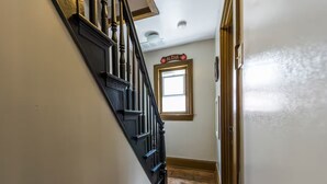 Una escalera de madera con barandillas negras que conduce a una habitación con una ventana y una puerta.