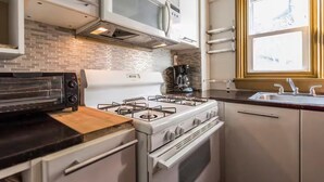 Una cocina compacta con estufa a gas, microondas, tostadora y ventana con vistas.