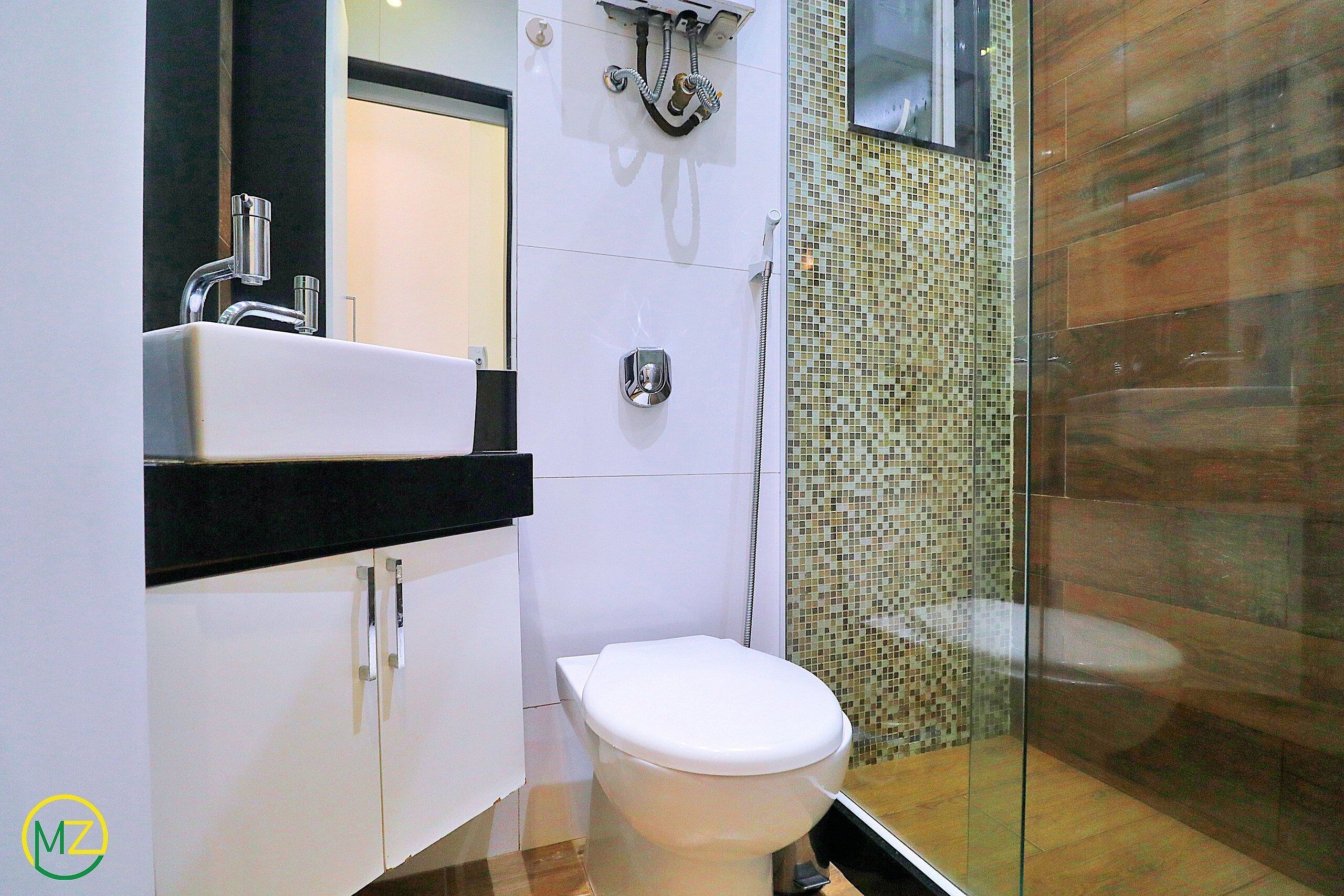 A modern bathroom with a white toilet, a sink with a black countertop, and a shower area with a tiled wall.