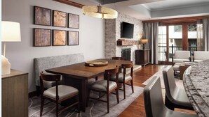 A modern dining area with a wooden table and chairs, a fireplace, and a large window with curtains. - Elegant 2 bedroom condo Vail. (Vail)