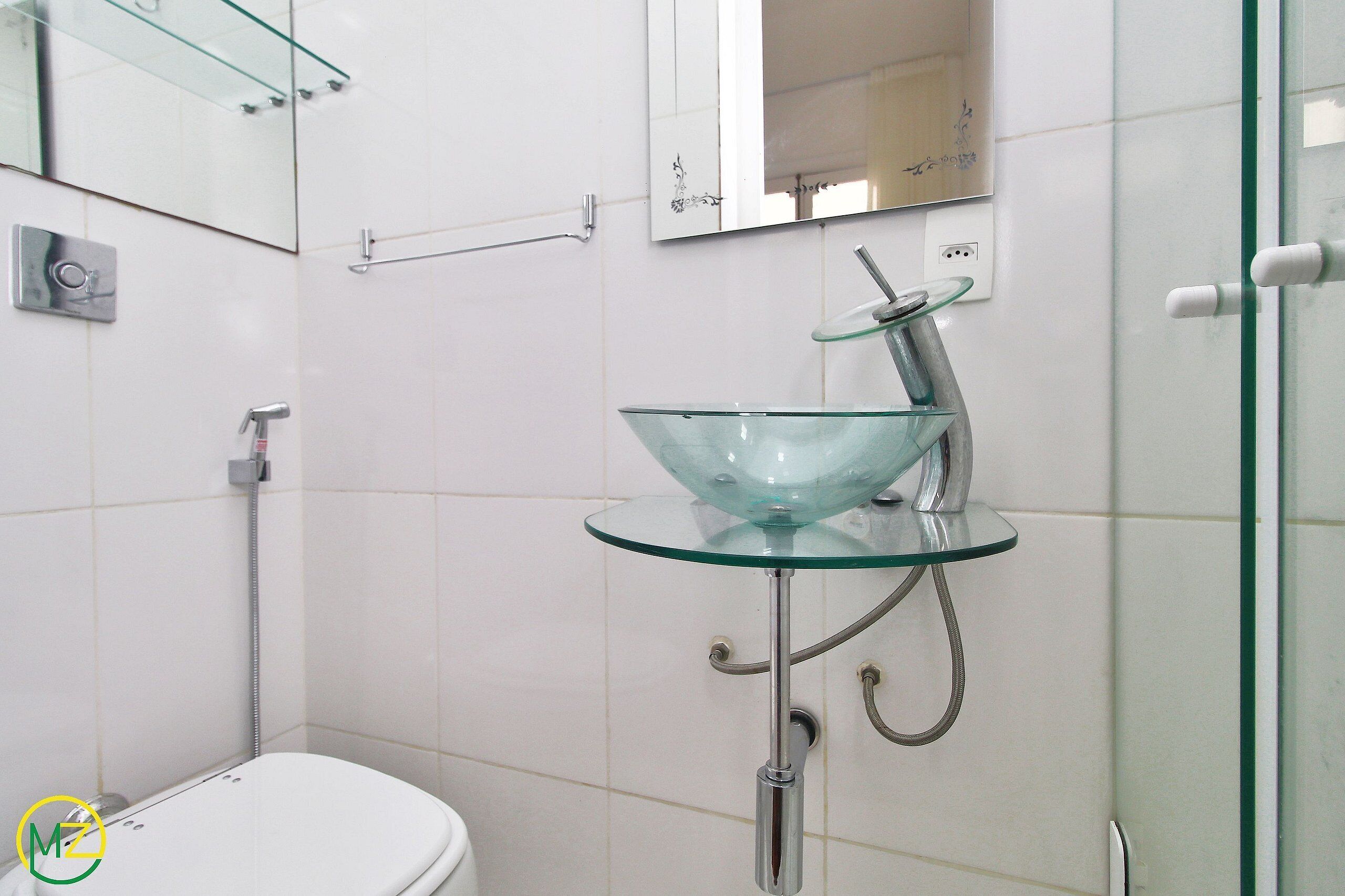 A bathroom with a glass sink, a toilet, and a shower.