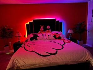 A bedroom with a bed featuring a large cartoon character design, multiple plush toys, and a modern headboard with neon lighting. - Enchanting Themed Villa Magic in Every Corner (Clermont)