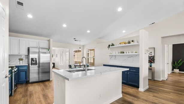 A modern kitchen with white cabinetry, a stainless steel refrigerator, and a central island. - Twilight Tunes - Pool, Glowing Arcade Experience (Indio)