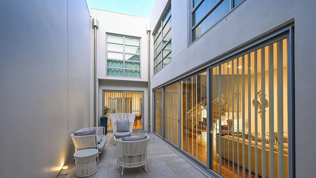 A modern outdoor patio area with wicker furniture, a glass door leading to an interior space, and a tiled floor. - Cozy 3-bedroom house with Wifi/AC and only mins from cafes and perth cbd. (Subiaco)