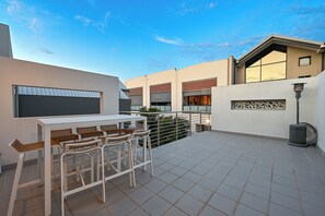 Eine Terrasse mit Tisch, Stühlen, einem Mülleimer und einer Zierwand.