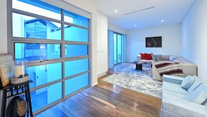 A spacious living area with a large sliding glass door leading to a balcony, a cozy seating area with a sofa and armchairs, and a fireplace with a decorative item on a side table. - Cozy 3-bedroom house with Wifi/AC and only mins from cafes and perth cbd. (Subiaco)
