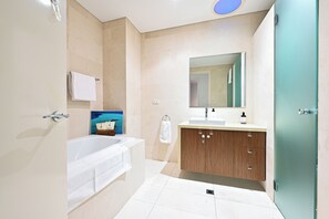 Ein modernes Badezimmer mit einer Badewanne, einem Waschbecken inklusive Spiegel und Holzschränken.