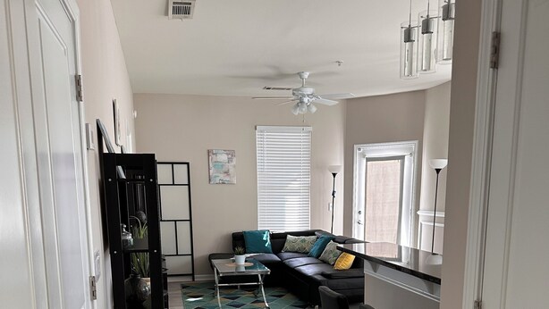 A modern living room with a sofa, a coffee table, and a dining area with a bar.