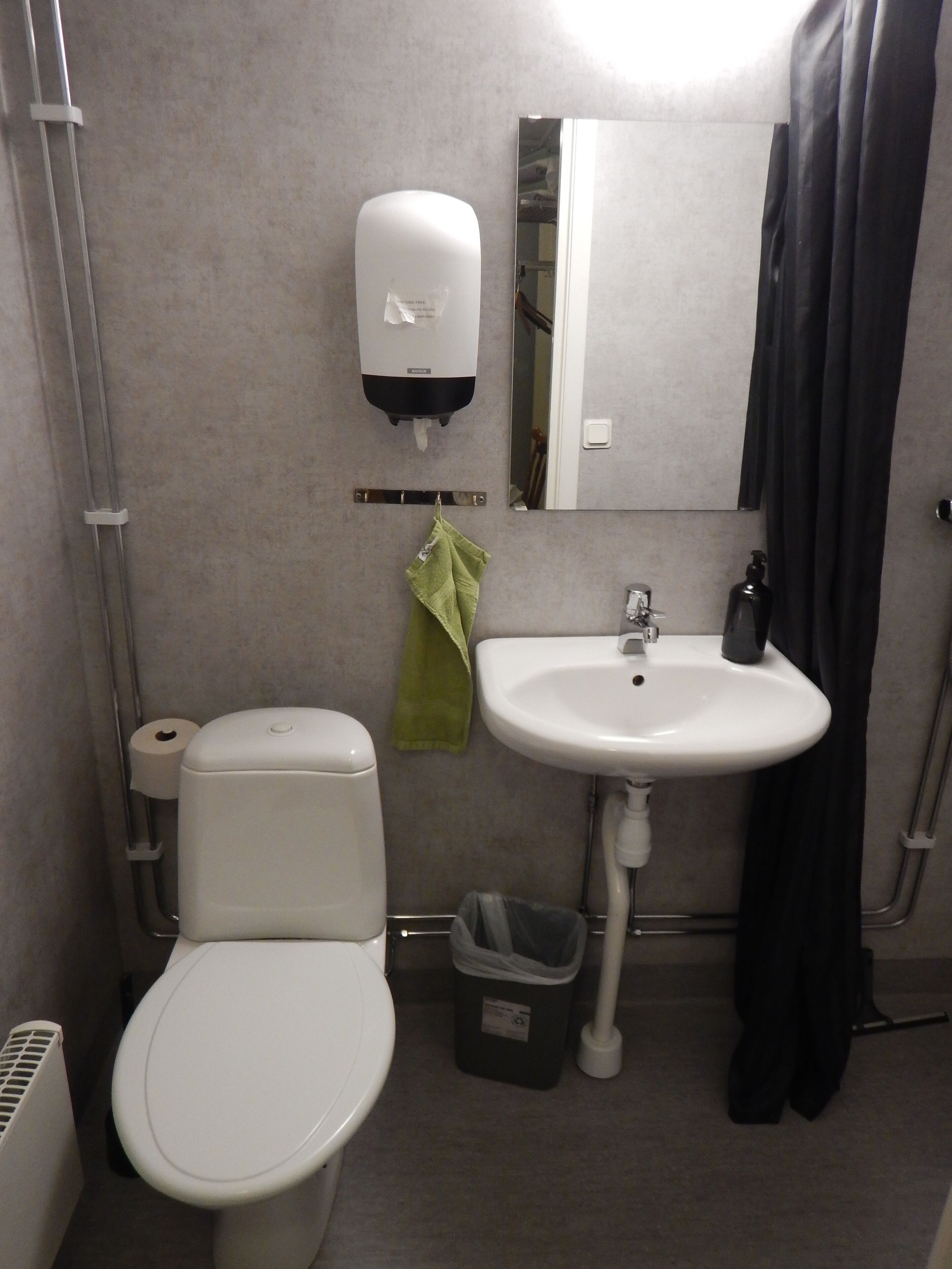 A bathroom with a toilet, sink, and hand dryer.