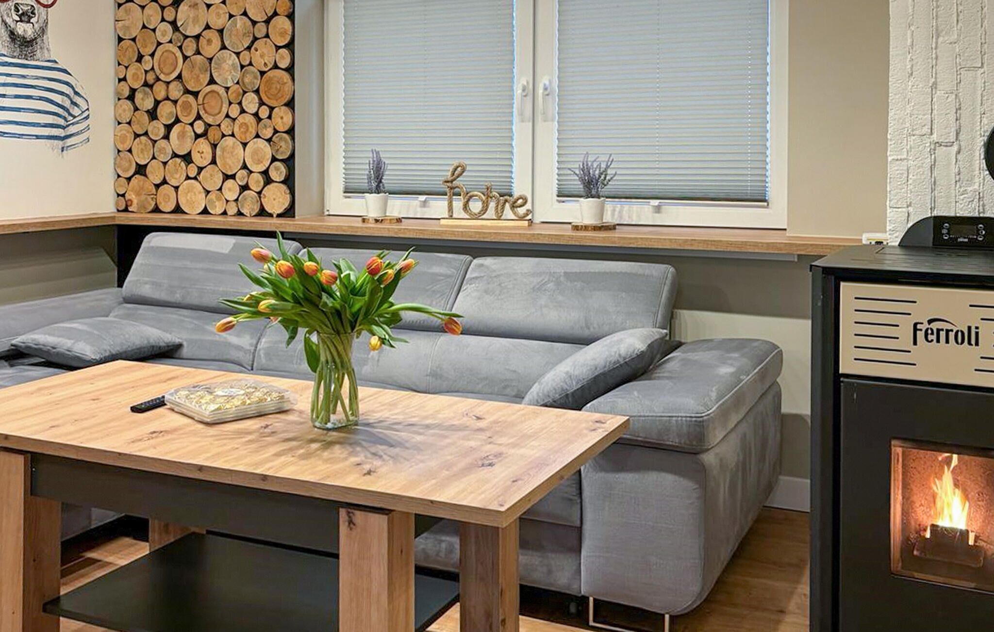 Ein modernes Wohnzimmer mit einem grauen Sofa, einem Holztisch und einem Kamin.