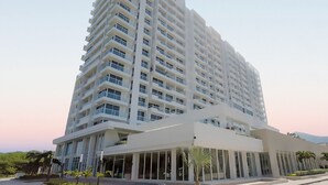Moderni korkea hotellirakennus, jossa on useita parvekkeita, suuret ikkunat ja tilava aula.