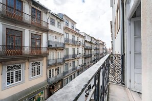 A narrow street with multi-story buildings, balconies, and a wrought iron railing. - Office Residence One (Oporto)