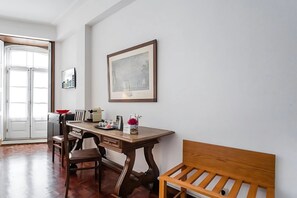 A room with a wooden desk, chairs, a bench, and a framed picture on the wall. - Office Residence One (Oporto)