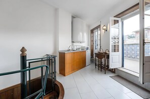 Una cocina con isla de madera, armarios blancos y vistas a través de una puerta abierta.