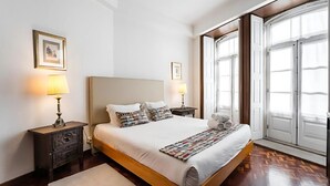 A neatly arranged bedroom with a large bed, two bedside tables, and a window with a view. - Office Residence Two (Oporto)