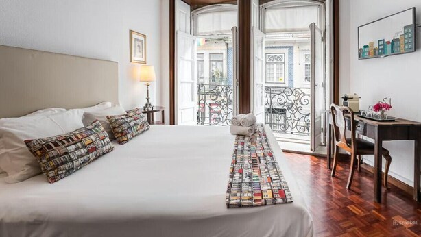 A hotel room with a large bed, a desk, and a balcony with a wrought iron railing. - Office Residence Two (Oporto)