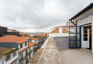 Une ruelle étroite entre deux bâtiments aux toits couverts de tuiles, un mur orné de motifs et une porte dotée d’un cadre bleu.