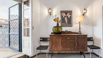 A room with a wooden cabinet, two chairs, a vase with flowers, and a poster on the wall.
