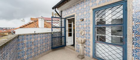 A rooftop terrace with blue and white patterned tiles, a blue door, and a small fountain.