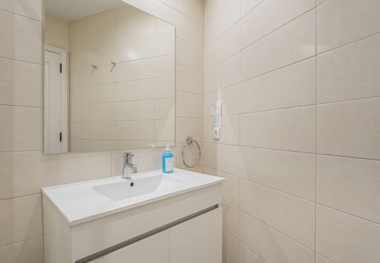Une salle de bain avec un lavabo blanc, un miroir et des murs carrelés.