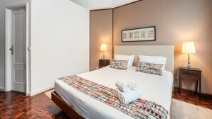 A neatly made bed with a patterned bedspread and pillows, two bedside tables with lamps, and a framed picture on the wall.
