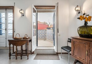 Una habitación con una mesa de madera, una silla, un armario y un florero con flores.