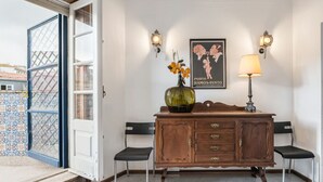 Une pièce comprenant un meuble en bois, deux chaises, un vase avec des fleurs et une affiche accrochée au mur.