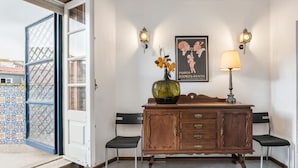 A room with a wooden cabinet, two chairs, a vase with flowers, and a poster on the wall. - Office Residence Six (Oporto)