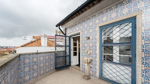 A rooftop terrace with blue and white patterned tiles, a blue door, and a window with a grid design. - Office Residence Six (Oporto)