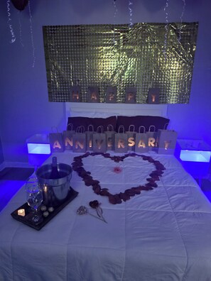 A bed with a heart-shaped arrangement of rose petals, a bottle of champagne, and a glass on a tray. - Cozy studio in superb Orlando with AC, WiFi (Orlando)