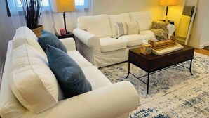 A living room with a white sofa, a dark wooden coffee table, and a patterned rug. - Highland: Driftless Fun Awaits (Highland)
