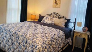 A bedroom with a large bed, a bedside table with a lamp, a wall clock, and a ceiling light fixture. - Highland: Driftless Fun Awaits (Highland)