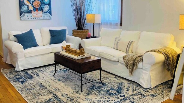 A living room with two white sofas, a coffee table, a decorative painting, a lamp, and a ceiling fan. - Highland: Driftless Fun Awaits (Highland)