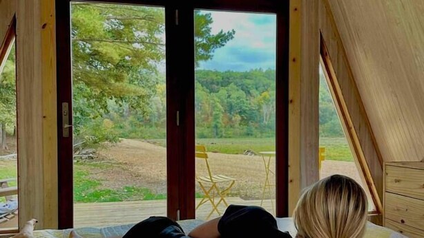 Ein Schlafzimmer mit großem Fenster, einem Bett und Blick ins Freie.