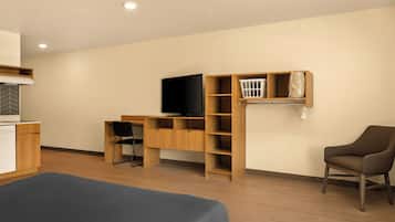 A modern room with a bed, a desk, a chair, a TV, and built-in shelving.