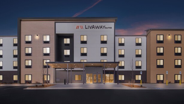 A modern hotel with a prominent entrance, multiple floors, and a clear sky. - LivAway Suites- Syracuse  (Syracuse)