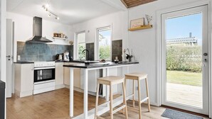 A modern kitchen with a central island, a built-in oven, and a large window. - 2 bedroom awesome home in Bogense (Bogense)