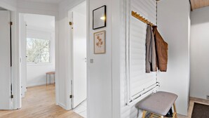 A hallway with white walls, a wooden floor, a bench, a radiator, and a window with a view of trees. - 2 bedroom awesome home in Bogense (Bogense)