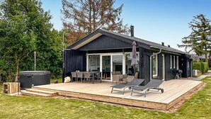 A modern cabin with a wooden deck, outdoor seating, and a hot tub. - 2 bedroom awesome home in Bogense (Bogense)